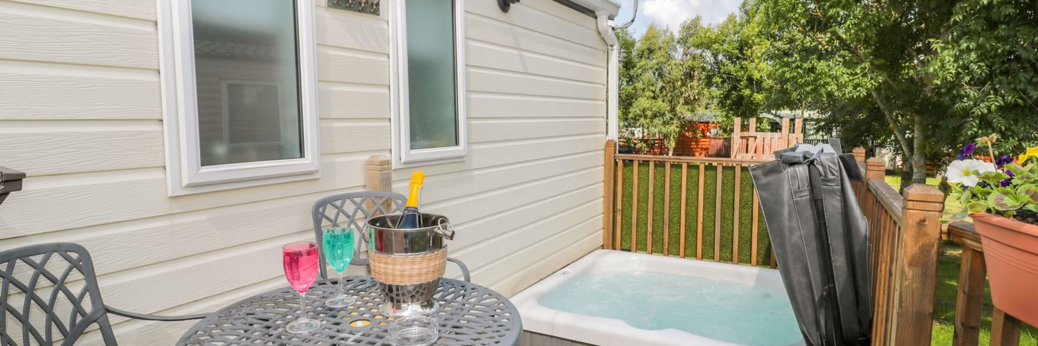 Side of a caravan with table and hot tub outside
