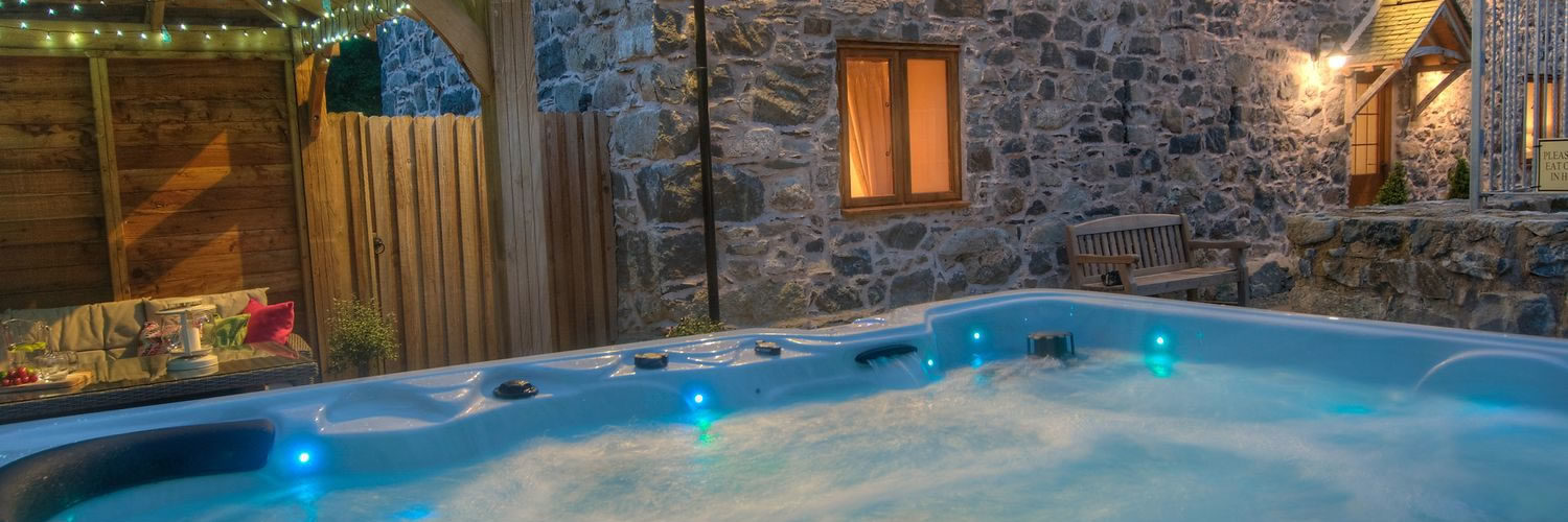 Barn at dusk with lighting and a large hot tub